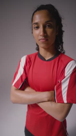 Vertical-Video-Studio-Portrait-Of-Female-Footballer-Wearing-Club-Kit-Against-Grey-Background